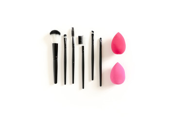Cosmetic brushes and sponges on white background