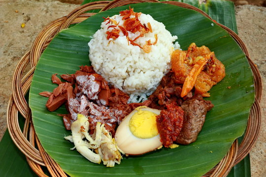 Nasi Gudeg. A signature rice dish from Jogjakarta. Jack fruit stew accompanied with spicy stew of cattle skin crackers and white chicken curry. In the background are the individual dish of gudeg meat