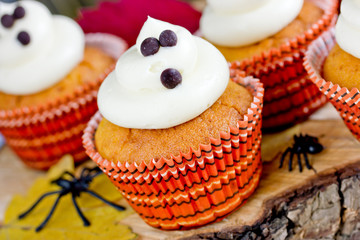 Halloween ghost cupcakes , homemade sweet pumpkin cakes with cream cheese frosting shaped funny ghosts for kid treats on Halloween party