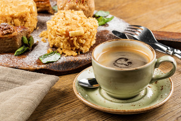 Cappuccino Cup with latte on wooden background. Beautiful foam, green ceramic Cup.