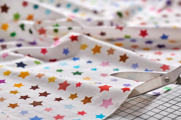 Obraz premium Process cutting fabric with a pattern of colorful stars by scissors on craft mat
