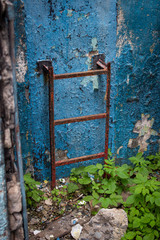 Rusty staircase on a background of blue wall with grass