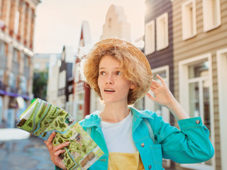 redhead young woman travel over West Europe and using paper map in unknown town. Travel photo