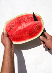 Man cutting a piece of fresh ripe watermelon.Vertical shot