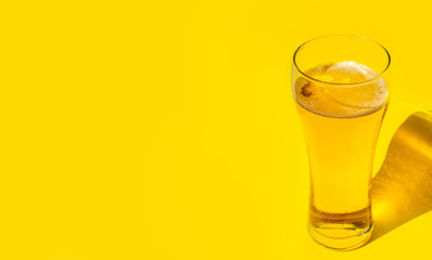 Beer. Cold Craft light Beer in a glass with water drops. Pint of Beer close up isolated on yellow color background with copy space.Oktoberfest concept.