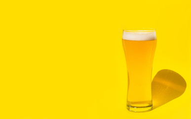 Beer. Cold Craft light Beer in a glass with water drops. Pint of Beer close up isolated on yellow color background with copy space.Oktoberfest concept.