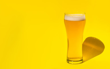 Beer. Cold Craft light Beer in a glass with water drops. Pint of Beer close up isolated on yellow color background with copy space.Oktoberfest concept.