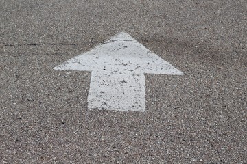 A close view of the white arrow on the concrete pavement.