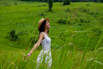 Girl breathing fresh air with white dress in a green meadow,enjoying in the sunny summer day.