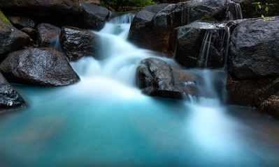Close up of Magical stream in the rainforest with soft flowing water like wool flowing through the cliff