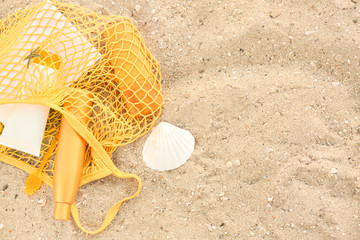 Fototapeta na wymiar Bag with sunscreen cream and book on sand beach