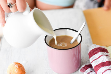 Woman pouring milk into coffee cup/latte/ Breakfast table-Starting a day