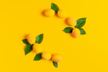 Ripe fresh apricots fruits with green leaves on yellow background. Flat lay, top view, copy space. Fresh organic apricots, diet vegan food. Creative Apricot pattern. Harvest concept