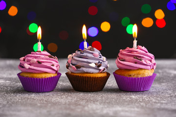 Tasty Birthday cupcakes on table against defocused lights