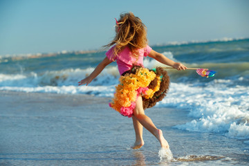 Naklejka premium Little girl at the sea. A child runs on the waves. 