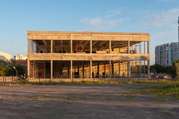 Unfinished abandoned building in the rays of the setting sun.
