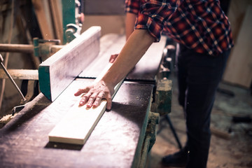 Young handsome joiner working with wood in his carpentry workshop