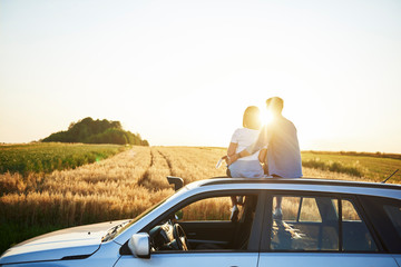 Rear view of affectionate couple catching a break during road trip