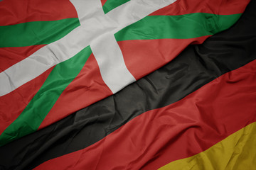 waving colorful flag of germany and national flag of basque country.