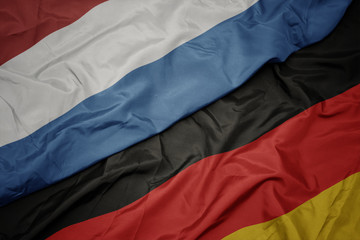 waving colorful flag of germany and national flag of luxembourg.