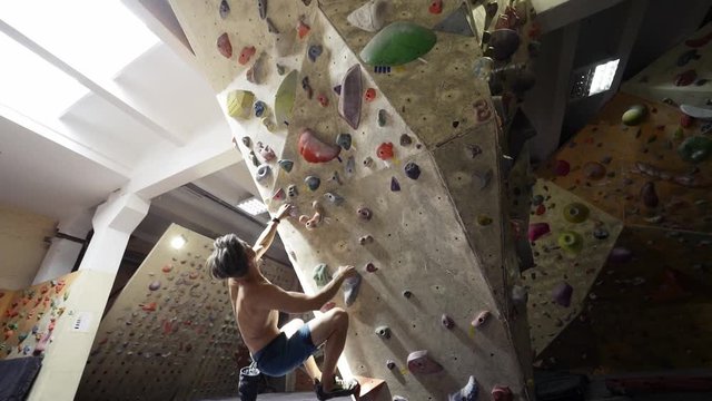 Adult man Rock climber with naked torso is Climbing At Inside climbing Gym. man Exercising At Indoor Climbing Gym Wall, FullHD stock footage