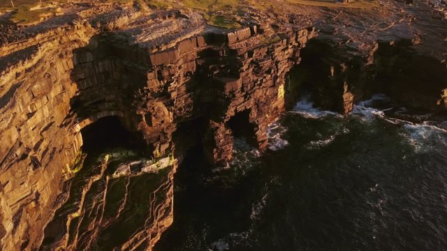 AERIAL PANNING LEFT Stunning rock shelters under Carrowmore Lacken cliff at sunset