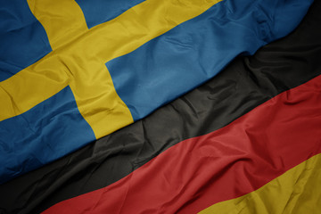 waving colorful flag of germany and national flag of sweden.