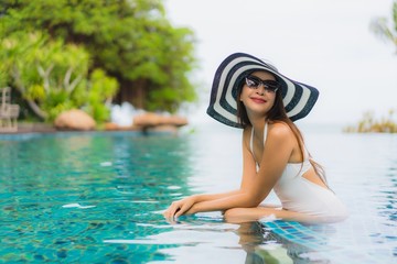 Portrait beautiful young asian woman smile happy relax around swimming pool in hotel resort