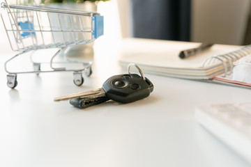 Car purchase concept. Empty shopping cart , car keys, calculator and notebook  on white table