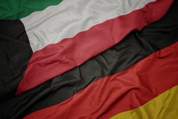 waving colorful flag of germany and national flag of kuwait.