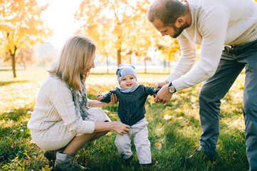Happy family outdoor activity. Young couple playing with their child in autumn park.