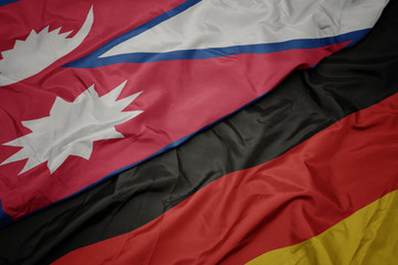 waving colorful flag of germany and national flag of nepal.