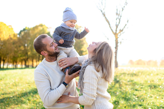 Happy Family Outdoor Activity. Young Emotional Parents Playing With Their Child In Sunny Day.