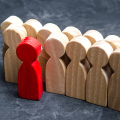 Wooden figures of people. The red man comes out with a team of workers. The concept of choosing a new leader. Choice of person. Hiring and recruiting. Human resource management. Selective focus