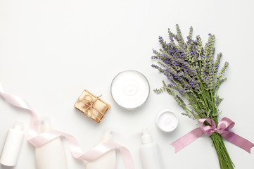 Fototapeta na wymiar Concept of natural spa cosmetics. Open jar of hand, face or body cream, white cosmetics bottles, soap and lavender on white background top view copy space. Natural herbal skin care products