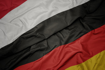 waving colorful flag of germany and national flag of yemen.