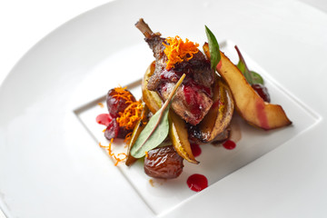 Duck leg with pear on a white plate