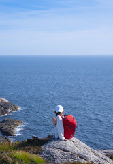 Fototapeta premium girl with red backpack doing walking on the lighthouse of Lindesnes, Norway