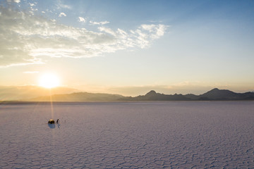 Ausgetrockneter See mit tiefen Rissen im Boden bei blauem Himmel mit Sonnenaufgang