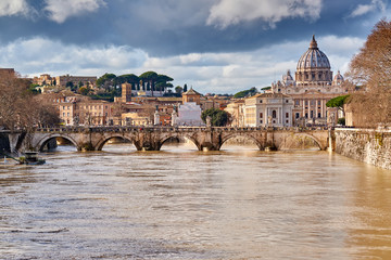 St. Peter's cathedral and Tiber river with high water in February. Saint Peter Basilica in Vatican city with Saint Angelo Bridge in Rome, Italy