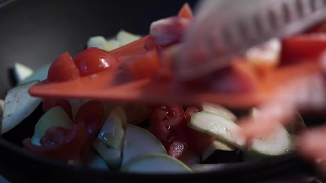 Close up view of colorful steaming vegetables frying on a pan being mixed and tossed up. Cooking process, healthy food, vegetarian cuisine. Delicious taste, homemade dish. Slow motion