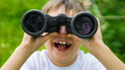 Little boy looking up through binoculars. focus on binoculars.