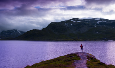 Fototapeta na wymiar Hiker with backpack on St?vatn lake at sunset, Norway