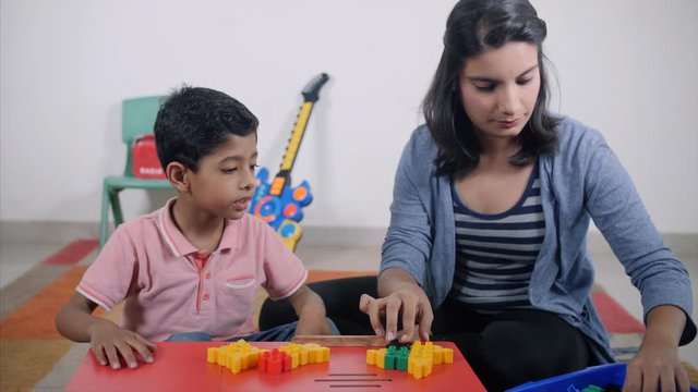 Shot of a young Indian mother and son playing with building blocks - Spending time at home during summer vacation. Attractive Indian mother and son playing at home. Making different shapes with blo...