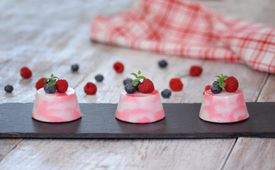 Delicious berry mousse desserts decorated with fresh raspberries, blueberries and mint.
