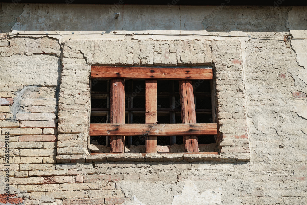 Poster old window of a brick building clogged with boards.