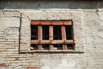 Old window of a brick building clogged with boards.