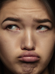 Fototapeta premium Close up portrait of young and emotional chinese woman. Highly detail photoshot of female model with well-kept skin and bright facial expression. Concept of human emotions. Looks sad, offended.