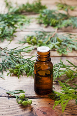 Thuja aroma essential oil in a glass jar on wooden background. Copy space. Selective focus.