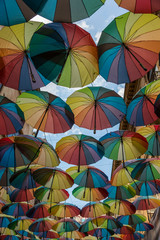 A small street in Bucharest covered by colorful umbrellas or parasols.